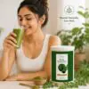 Woman drinking a green smoothie beside Ultra Health Care Organic Moringa Powder in a bright natural wellness setting.
